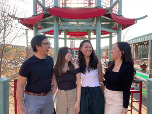 Meilia's four founders standing, smiling, and laughing infront of a red and green pagoda