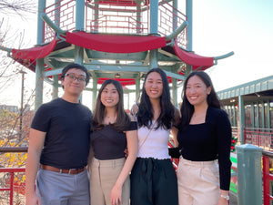 Meilia's four founders standing and smiling infront of a red and green pagoda