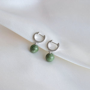 Closeup of silver jade hoop earrings on cloth