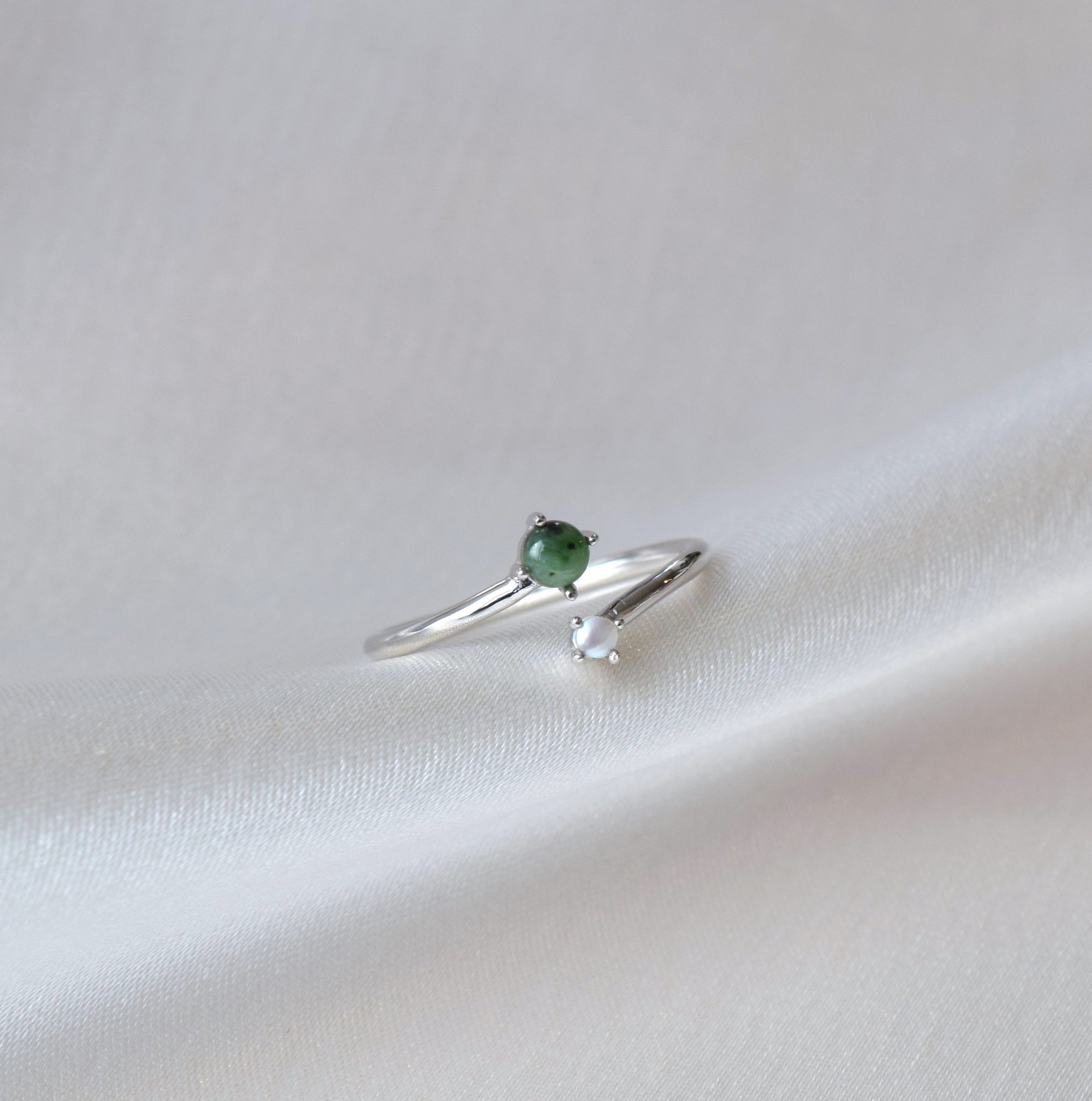 Closeup of silver jade and pearl ring on cloth