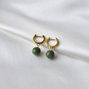 Closeup of gold jade hoop earrings on cloth