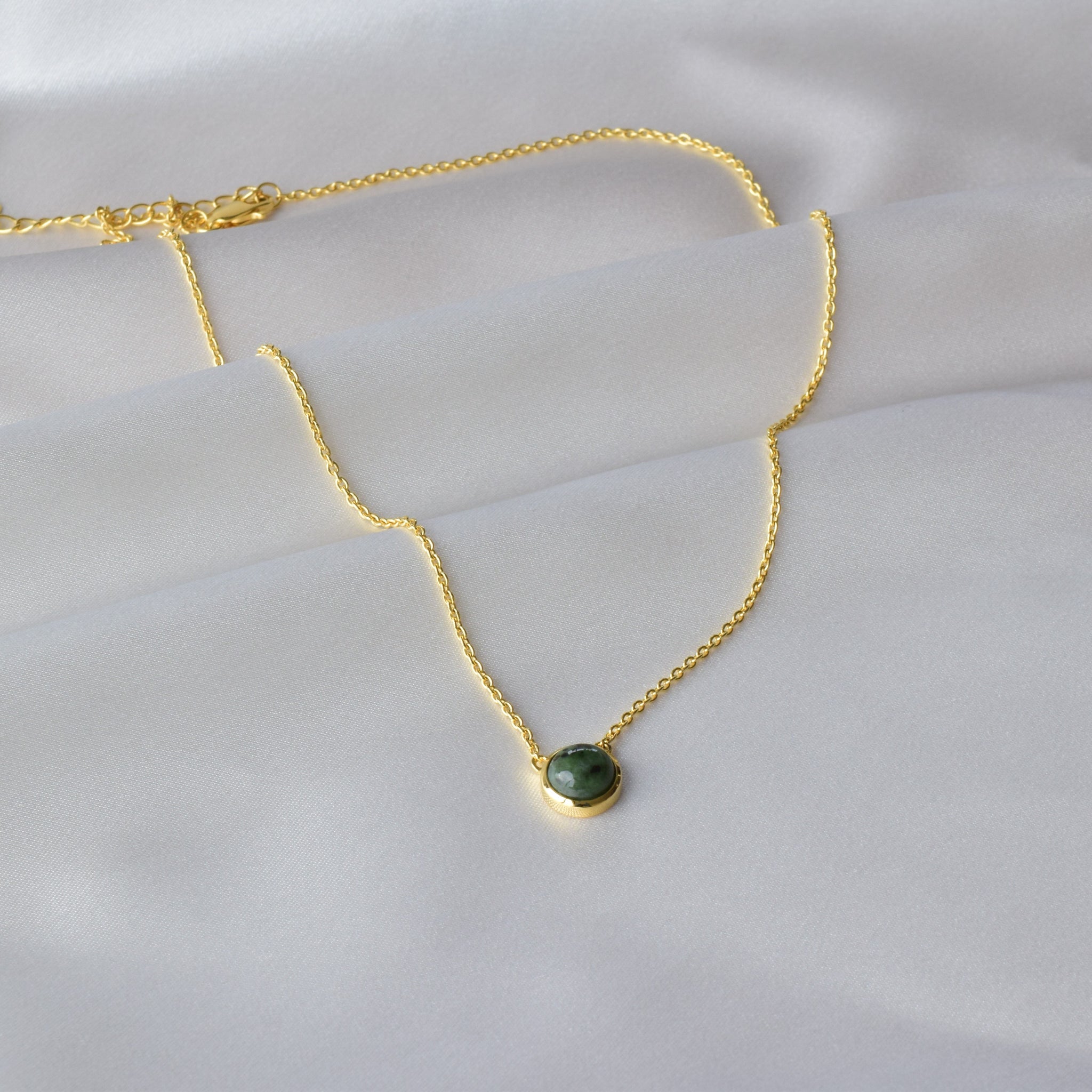 Gold jade necklace displayed in a wave pattern on Cloth