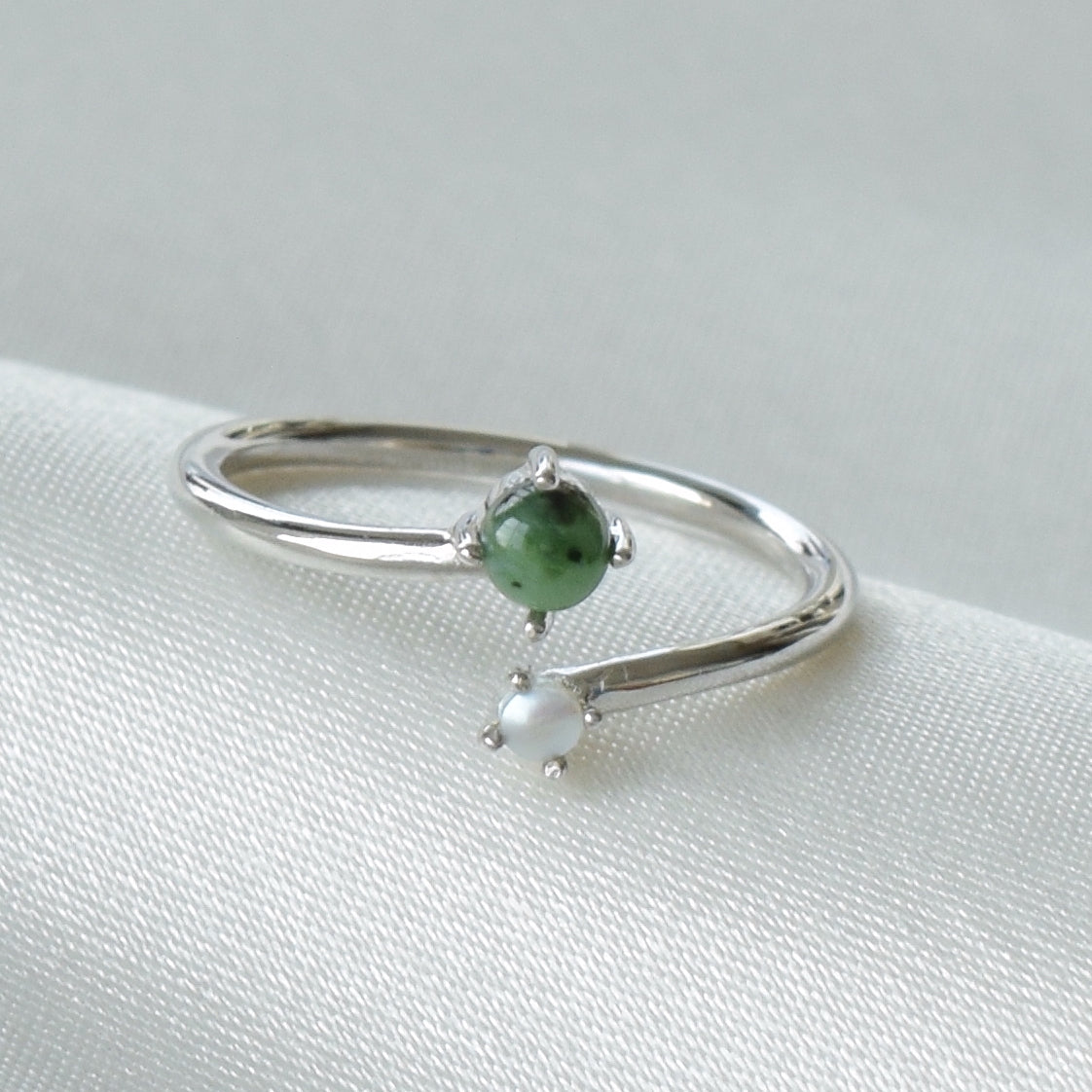 Closeup of silver jade and pearl ring on cloth