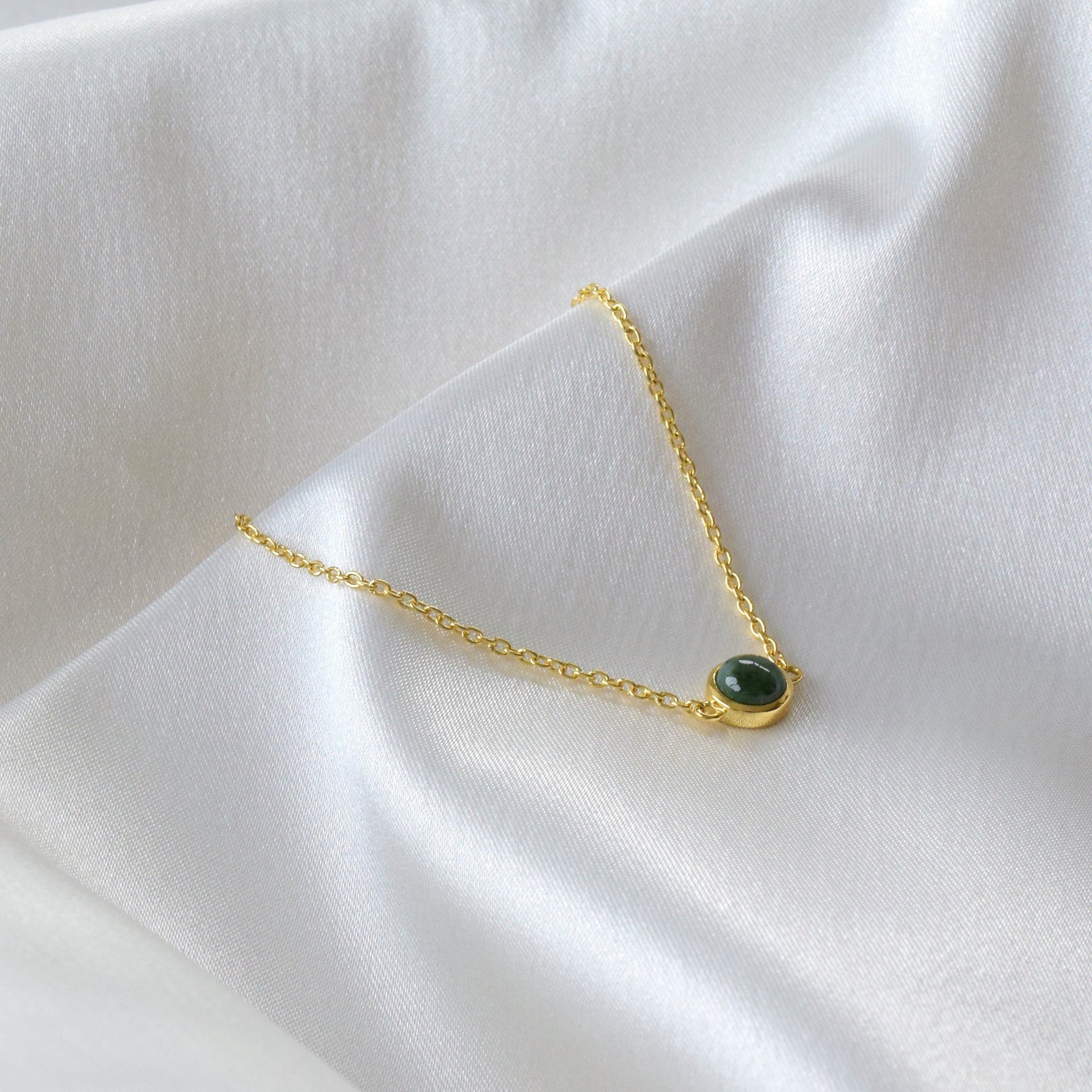 Gold jade bracelet displayed in a V-shape on cloth