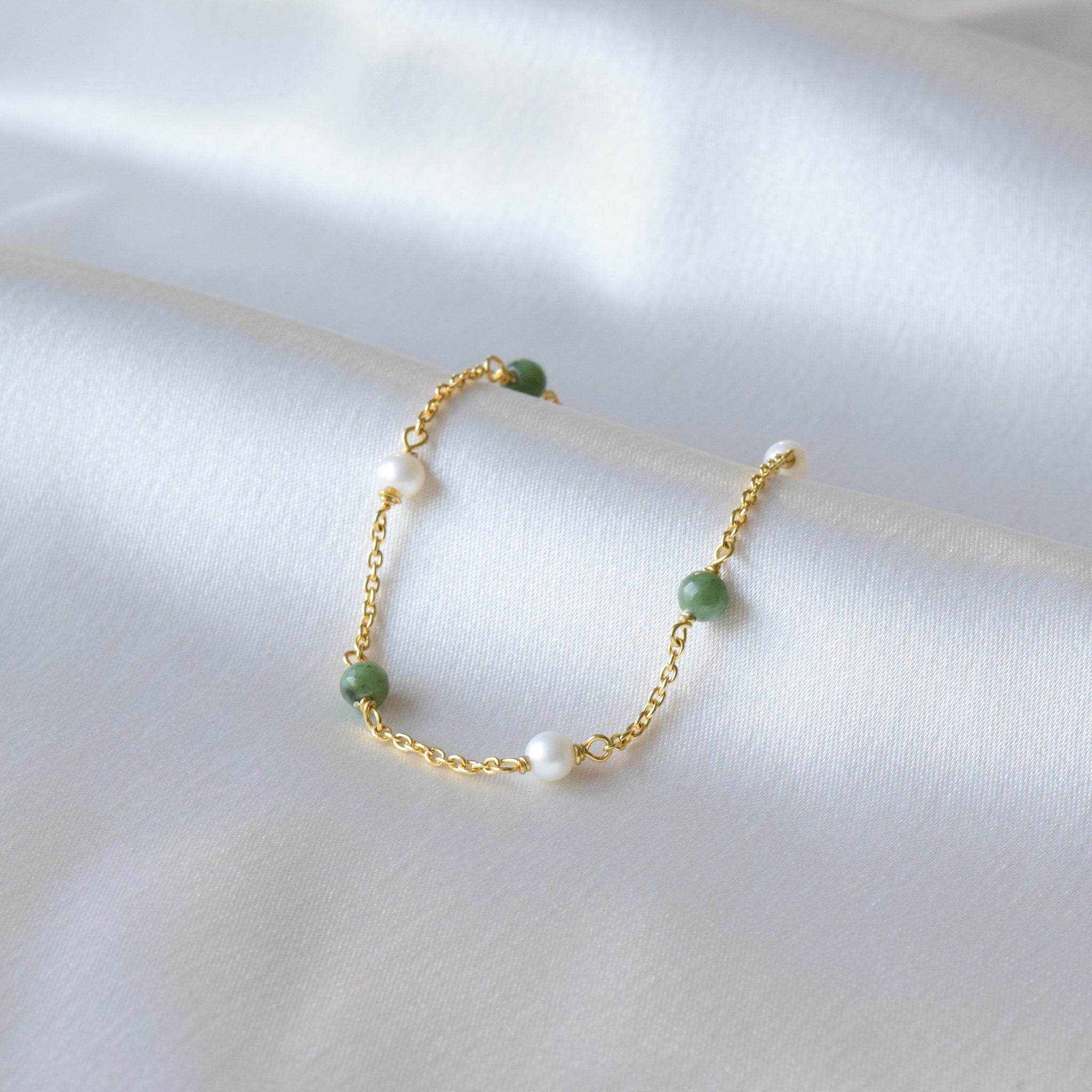 Gold Jade and Pearl Bracelet leaning on cloth