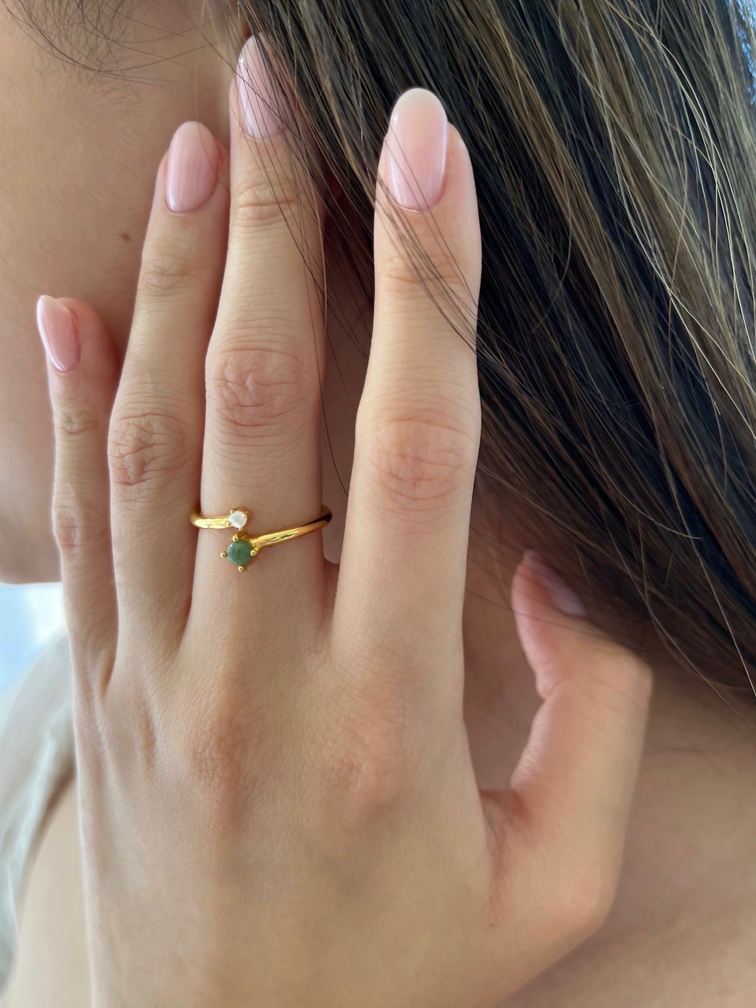 Woman wearing a gold and jade pearl ring 