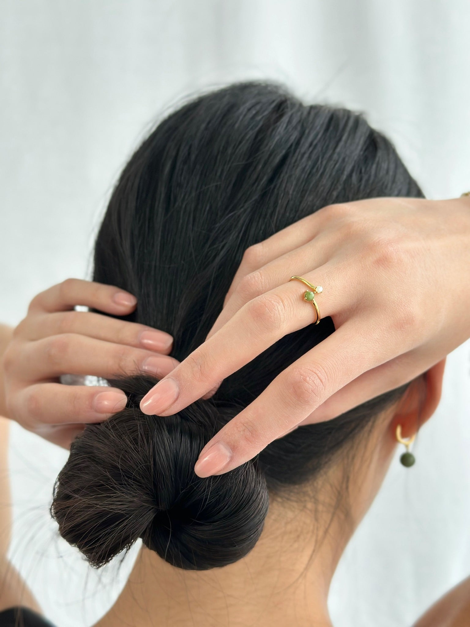 Asian woman wearing a gold jade and pearl ring placed on her hairbun