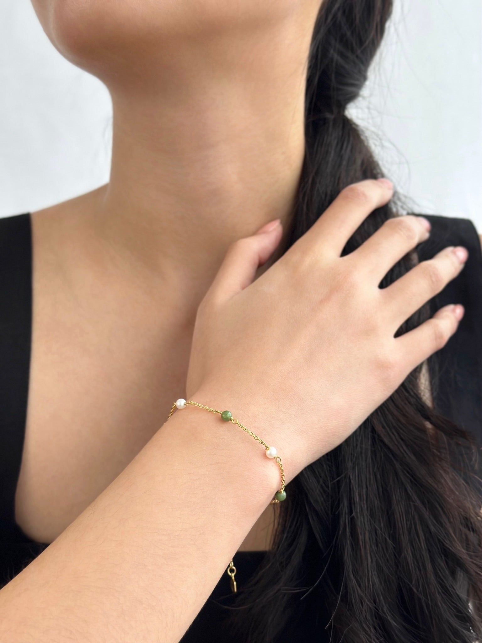 Gold Jade and Pearl Bracelet worn by woman in black dress 