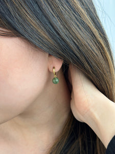 Closeup of woman wearing gold jade hoop earrings