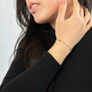 Woman wearing black turtleneck with hand on neck displaying silver jade and pearl bracelet