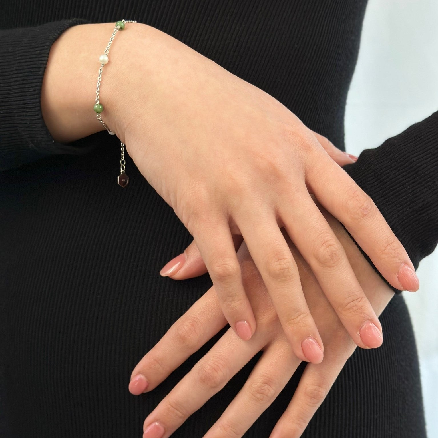 Two hands crossed displaying silver jade and pearl bracelet