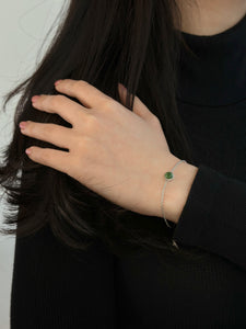 Woman with hand on her shoulder wearing a silver jade bracelet