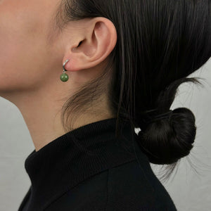 Woman in black turtleneck displaying silver jade hoop earrings