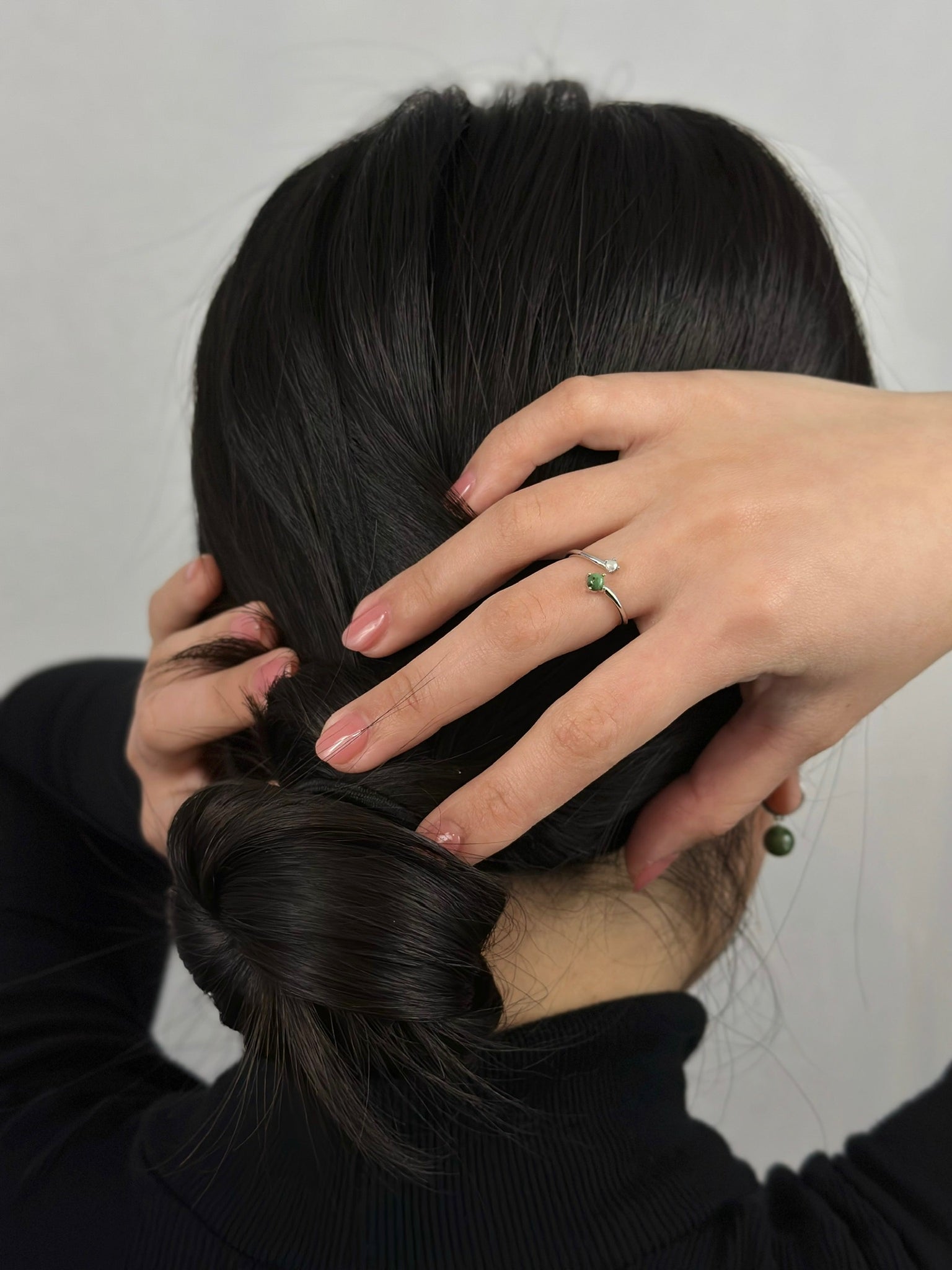 Woman wearing black turtleneck and jade earrings displaying silver jade and pearl ring