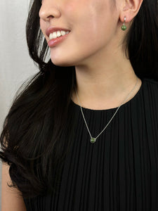 Woman wearing black dress displays silver jade earrings and silver jade necklace