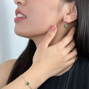 Woman with hand on her neck wearing silver jade hoop earrings and silver jade bracelet