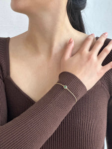 Woman in brown dress displaying gold jade bracelet on her wrist