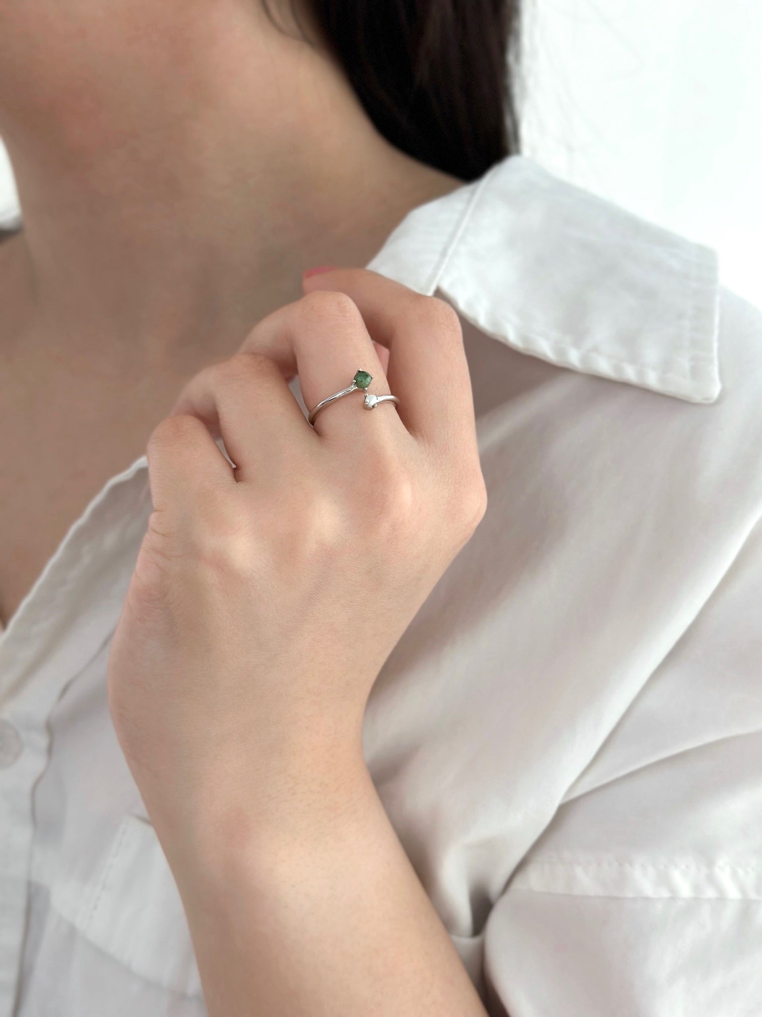 Woman in white dress shirt holding her shirt collar displaying a silver jade and pearl ring