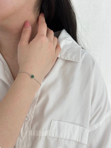 Woman with hand on her neck displaying silver jade bracelet