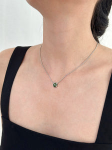 Woman wearing black dress displays silver jade necklace