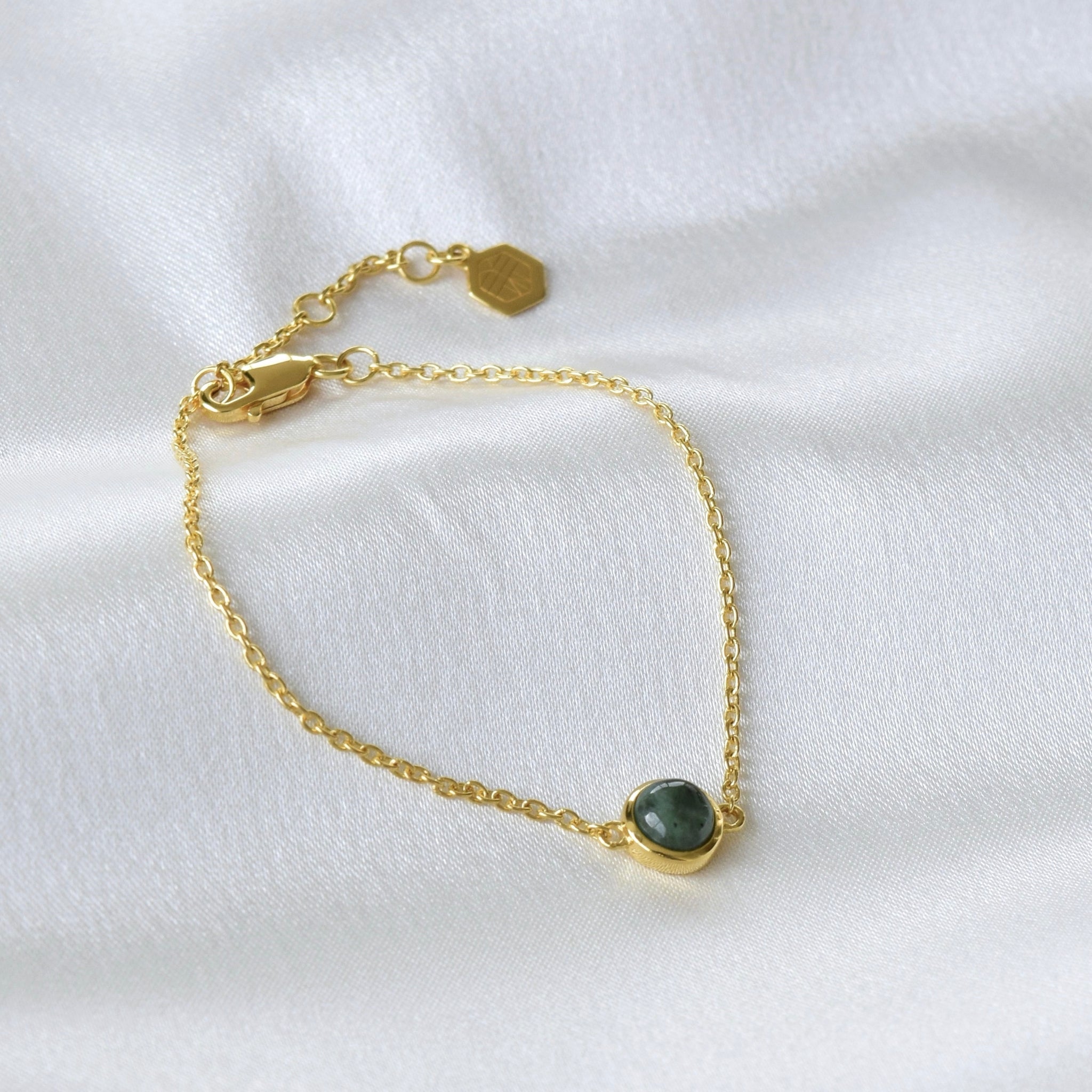 Gold jade bracelet displayed in a circle shape on cloth